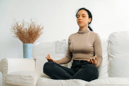 Foto de Mujer afroamericana joven practica meditación consciente crucial en casa sala de estar para mejorar la salud mental fuerza y pacífica hermosa vida - Imagen libre de derechos
