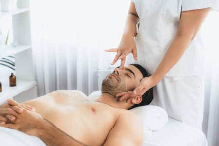 Photo for Caucasian man enjoying relaxing anti-stress head massage and pampering facial beauty skin recreation leisure in dayspa modern light ambient at luxury resort or hotel spa salon. Quiescent - Royalty Free Image