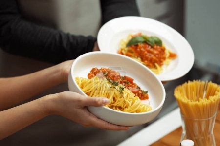 Photo for Close up of hand couple chef influencers completely cooked spaghetti with meat topped with tomato sauce special dish on live chanel. Concept of serving healthy food at modern home studio. Postulate. - Royalty Free Image