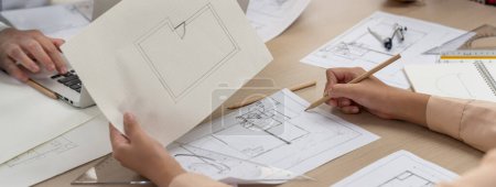 Photo for Skilled architect drafts blueprint on paper while male engineer works on laptop in architectural office. Professional engineer and architect collaborate on architectural project. Closeup. Delineation. - Royalty Free Image