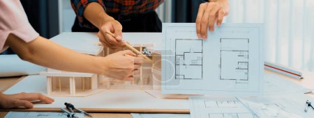 Photo for Cropped image professional architect hand compare construction between blueprint and house model while coworker pointing the difference point. Creative and teamwork concept. Closeup. Burgeoning. - Royalty Free Image