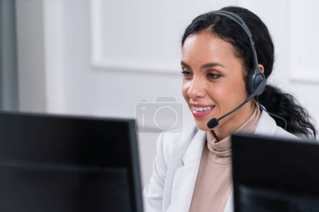 Photo for African American young businesswoman wearing headset working in office to support remote crucial customer or colleague. Call center, telemarketing, customer support agent provide service on video call - Royalty Free Image