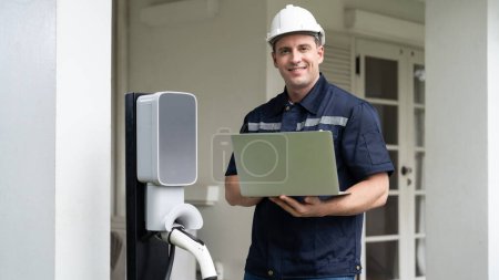 Photo for Qualified technician working on home EV charging station installation, making troubleshooting and configuration setup on charging system with laptop for EV at home. Panorama Synchronos - Royalty Free Image