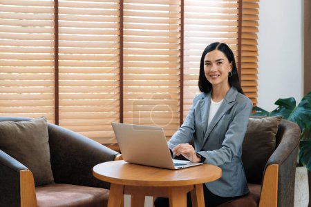 Photo for Portrait of happy and smiling female psychologist portrait using laptop for online video call on mental diagnostic with patient in psychiatrist office room. Remote mental treatment therapy. Blithe - Royalty Free Image
