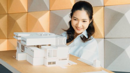 Photo for Skilled attractive architect engineer holds architect model while checking mistake point carefully. Project manager inspect architectural model by lifting left side and right side. Manipulator. - Royalty Free Image