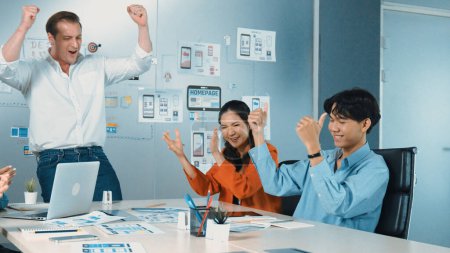 Photo for Diverse business team celebrate successful project by clapping hands and raising arm in the air. Group of happy corporate businesspeople smiling while sitting in business meeting. Manipulator. - Royalty Free Image