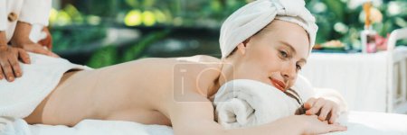 Photo for Beautiful young woman lies on white spa bed during having back massage. Attractive caucasian woman having back massage surrounded by natural environment. Relaxing and healthy concept Tranquility. - Royalty Free Image