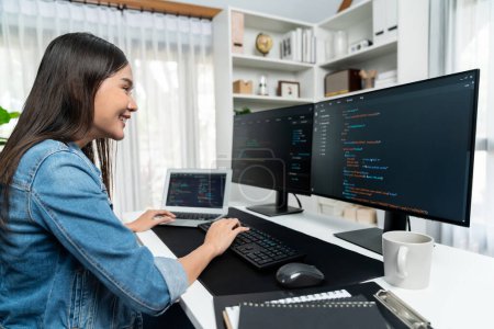 Photo for Young Asian in IT developer creating with typing online information on pc with coding program data of website application, wearing jeans shirt. surrounded by safety analysis two screens. Stratagem. - Royalty Free Image