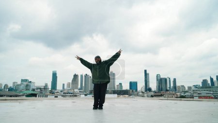 Photo for Motion shot of B-boy dance performance by professional street dancer at rooftop with sky scrapper, city view. Attractive asian hipster show energetic footstep. Outdoor sport 2024. Endeavor. - Royalty Free Image