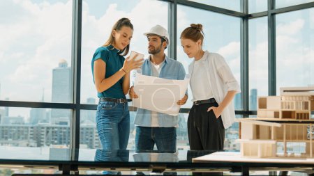 Photo for Professional architect engineer team talking, sharing, brainstorming about design while manager hold at project plan. Young architect holding plan while manager listen and point at plan. Tracery - Royalty Free Image