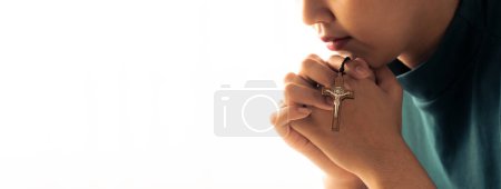 Photo for Praying female hand holding cross while praying to god faithfully. Concept of hope, religion, faith, christianity and god blessing for happiness. Bright light, white blurring background. Burgeoning. - Royalty Free Image