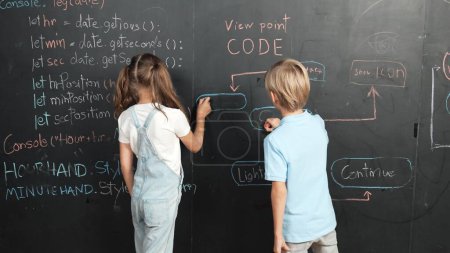 Photo for Caucasian girl and smart boy writing blackboard with engineering prompt or coding, programing system written in STEM technology classroom. Young cute student working together at blackboard. Erudition. - Royalty Free Image