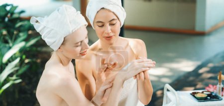Photo for A portrait of two beautiful caucasian woman in white towel using homemade facial mask rounded by peaceful natural environment at outdoor. Healthy and beauty concept. Blurring background. Tranquility. - Royalty Free Image