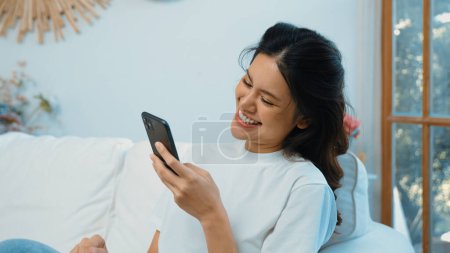 Photo for Young woman using smartphone browsing for online shopping E commerce by online payment gateway at vivancy home. Modern and convenience online purchasing make secure and convenient purchases. - Royalty Free Image