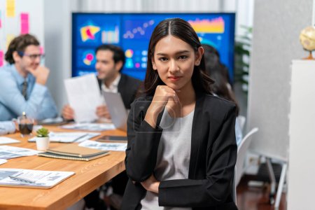 Photo for Portrait of happy young asian businesswoman or analyst looking at camera with her colleague analyzing data analysis in dynamic business strategy investment planning meeting. Meticulous - Royalty Free Image