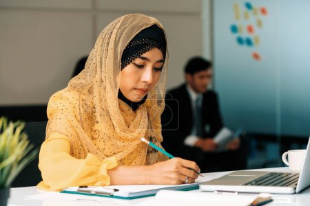 Foto de Exitosa empresaria musulmana de Oriente Medio que trabaja en el cargo. Concepto de éxito empresarial internacional. BARROS - Imagen libre de derechos