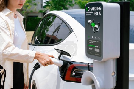 Photo for Young woman put EV charger to recharge electric cars battery from charging station. Alternative energy and rechargeable EV car for sustainable environmental friendly travel concept. Expedient - Royalty Free Image