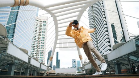 Photo for Low angle camera of asian hipster practice break dancing footstep or b-boy performance while wearing headphone. Freestyle dance, break dance, street dance. Lively mood. Outdoor sport 2024. Sprightly. - Royalty Free Image