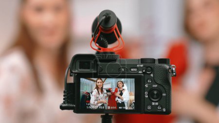 Photo for Rear view behide camera screen display two women influencer shoot vlog video review clothes prim social media or blog. Girls with apparel studio lighting for live streaming marketing recording session - Royalty Free Image