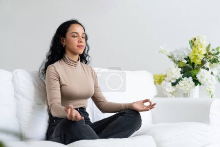 Téléchargez les photos : Jeune femme afro-américaine pratique la méditation consciente cruciale à la maison salon pour améliorer la force de la santé mentale et paisible belle vie - en image libre de droit