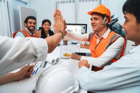Photo for Diverse group of civil engineer and client celebrate and high five after make successful agreement on architectural project, reviewing construction plan and building blueprint at meeting table.Prudent - Royalty Free Image