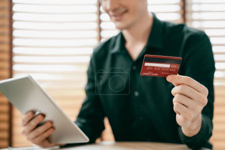Photo for Young man using tablet with credit card for internet banking, online shopping E commerce by online payment gateway at home office. Modern and convenience online purchasing with debit card. Unveiling - Royalty Free Image
