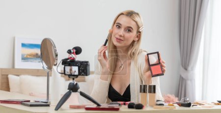 Photo for Young woman making beauty and cosmetic tutorial video content for social media. Beauty blogger smiles to camera while showing how to beauty care to audience or followers. Panorama Blithe - Royalty Free Image