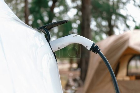 Photo for Electric car recharging battery at outdoor EV charging station at natural vacation campsite, alternative and sustainable energy technology eco-friendly car with holiday and travel concept. Perpetual - Royalty Free Image