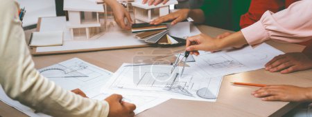 Photo for Professional architect team select sustainable house materials while skilled engineer using divider measure blueprint with house model and color palette placed on meeting table. Closeup. Variegated. - Royalty Free Image