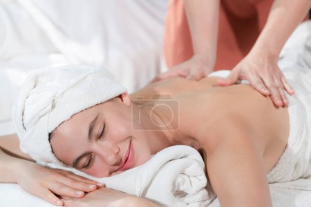 Téléchargez les photos : Belle femme caucasienne ayant massage du dos par masseur professionnel thaïlandais. Une femme séduisante se sent profondément dans la relaxation entourée d'arôme et d'huile essentielle. Concept relaxant et calme. Tranquillité. - en image libre de droit