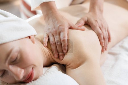Téléchargez les photos : Belle jeune femme a reçu un massage du dos sur un lit de spa de masseuse professionnelle. Attrayant femelle se détend par les mains habiles du massothérapeute. Entouré de nature. Tranquillité. - en image libre de droit