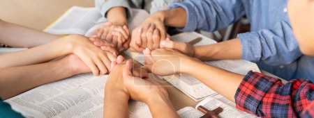 Cropped image of diversity people hand priing together at wooden church on bible book while hold hand together with believe. Concept d'espoir, de religion, de foi, de bénédiction divine. Émergence.