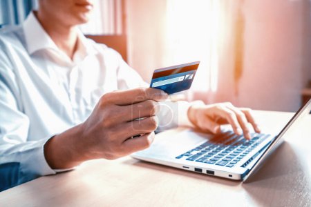 Téléchargez les photos : Jeune homme utiliser la carte de crédit pour faire des achats en ligne sur l'application d'ordinateur portable ou site Web. E-commerce et concept d'achat en ligne. uds - en image libre de droit