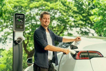 Homme recharge batterie pour voiture électrique pendant le voyage en voiture EV voyage dans la forêt naturelle ou parc national. Voyage écologique pendant les vacances et les vacances. Exalt.