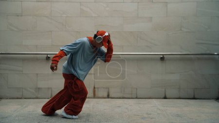 Photo for Handsome choreographer practice street dance in gray background. Young attractive b-boy dancer perform while wearing stylish cloth. Feeling of lively step. Copy space. Outdoor sport 2024. Sprightly. - Royalty Free Image