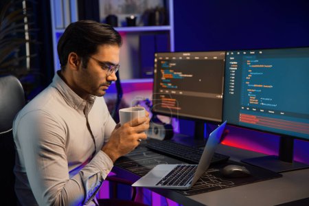 Photo for Smart IT developer drinking coffee cup while working in software development coding on pc screen, presenting program application update online website database at neon lighting cyber office. Surmise. - Royalty Free Image