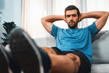 Athletischer Körper und aktiver, sportlicher Mann mit Möbeln zur effektiven gezielten Muskelaufbauübung bei fröhlicher Heimübung als Konzept eines gesunden, fitten Körpertrainingsstils.
