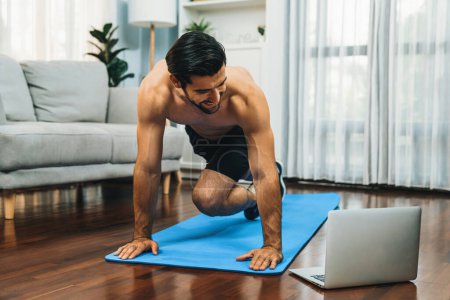 Photo for Athletic and sporty man doing mountain climber on fitness mat during online body workout exercise session for fit physique and healthy sport lifestyle at home. Gaiety home exercise workout training. - Royalty Free Image