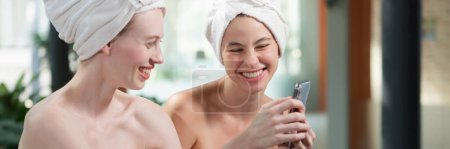 Photo for Couple of young beautiful women with beautiful skin in white towel taking a photo together at outdoor surrounded by peaceful natural environment. Beauty and healthy spa concept. Tranquility. - Royalty Free Image