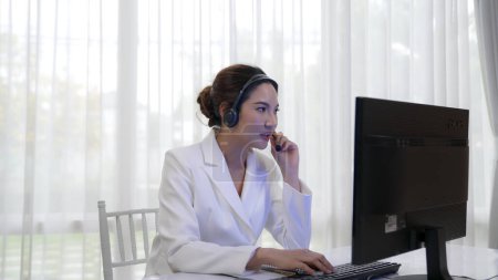 Photo for Businesswoman wearing vivancy headset working in office to support remote customer or colleague. Call center, telemarketing, customer support agent provide service on telephone video conference call - Royalty Free Image