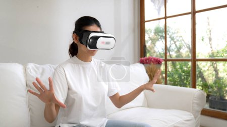 Photo for Young woman using virtual reality VR goggle at home for vivancy online shopping experience. The virtual reality VR innovation optimized for female digital entertainment lifestyle. - Royalty Free Image