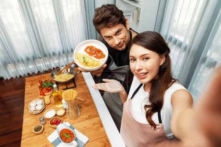 Photo for Making photo selfie in couple chef influencers completely cooked spaghetti with meat topped with tomato sauce special dish recording on camera, serving healthy food at modern home chanel. Postulate. - Royalty Free Image