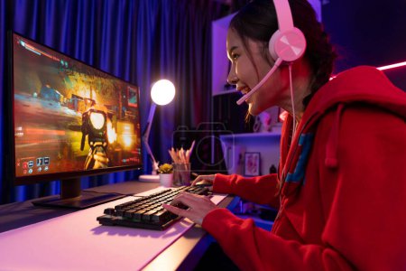 Anfitrión canal de la joven hermosa corriente de juegos asiáticos, jugando juego en equipo de batalla con multijugador o solo en el buque de guerra en la pantalla, con auriculares de color pastel en la sala de luz de neón digital. Estratagema.