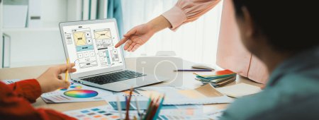 Photo for Cropped image of interior designer team discuss the material color while laptop displayed website wireframe designs for mobiles app and website. Creative design and business concept. Variegated. - Royalty Free Image