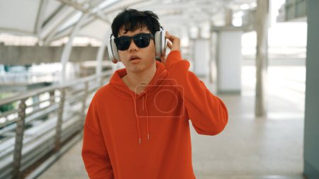 Photo for Dancer listen to hip hop music while sing along and walking at corridor. Handsome hipster wearing stylish cloth and headphone express feeling of lively or happy mood. Outdoor sport 2024. Sprightly. - Royalty Free Image