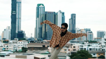 Photo for Hispanic break dancer practice B-boy footsteps at roof top with urban city view or sky scrapper. Young modern dancing group doing hip hop movement. Style,fashion,action. Outdoor sport 2024. Endeavor. - Royalty Free Image