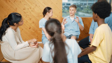 Photo for Attractive boy sharing experience during attend in group therapy. Highschool student talking about way to recovery stress while surrounded with multicultural friend listeing carefully. Edification. - Royalty Free Image