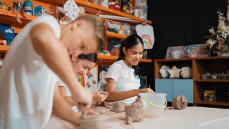 Niños multiculturales cualificados esculpiendo arcilla en taller de cerámica. Inteligente diversas escuelas secundarias que trabajan en la arcilla mediante el uso de equipos de antojos en la lección de arte. Concepto de actividad creativa. Educación. Edificación.