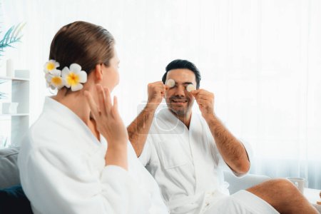 Photo for Blissful couple in bathrobe playing with cucumber and enjoying daylight ambiance spa salon resort or hotel during holiday. Pampering face spa and skincare treatment with essence relaxation. Quiescent - Royalty Free Image