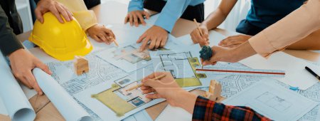 Photo for Professional architect cooperate with engineer discussing the use of green design in eco house project on table with blueprint and architectural equipment scatter around. Closeup. Delineation. - Royalty Free Image